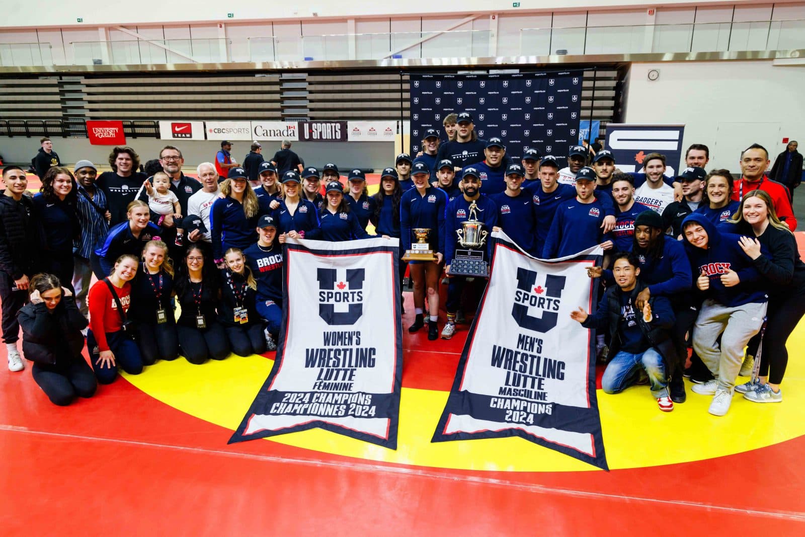 Brock wrestling team group photo with the 2024 U SPORTS men's and women's championship banners.